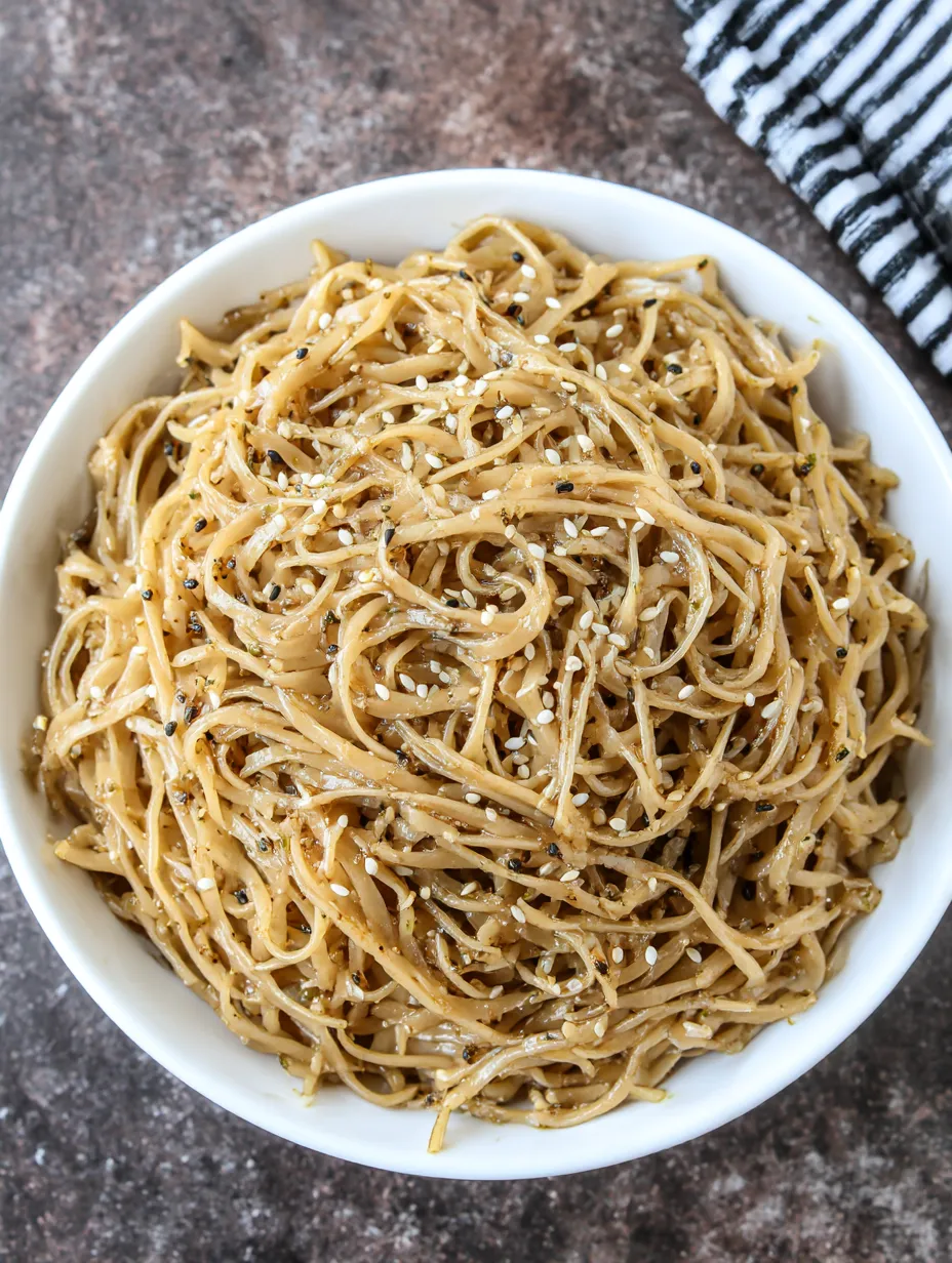 A bowl of noodles with sesame seeds on top.