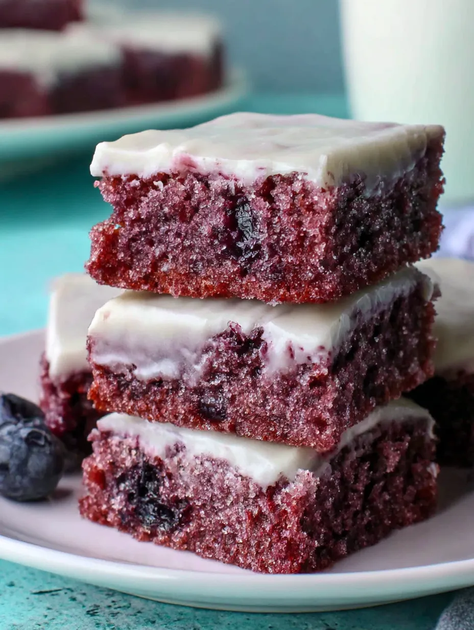 A stack of brownies with blueberries on top.