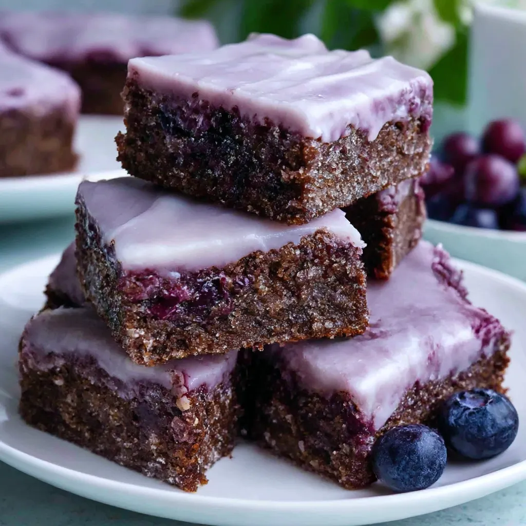 A stack of brownies with blueberries on top.